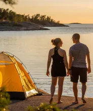 Par campar med gult tält på klippor vid havet på Åland.