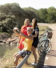 Kvinnor med cyklar som stannat vid brobank för fotografering.