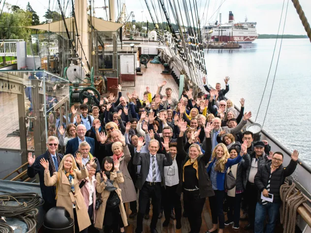 Konferensgrupp som vinkar mot kameran på fartyget Pommerns däck.