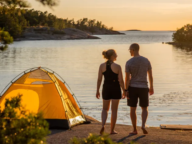 Par campar med gult tält på klippor vid havet på Åland.