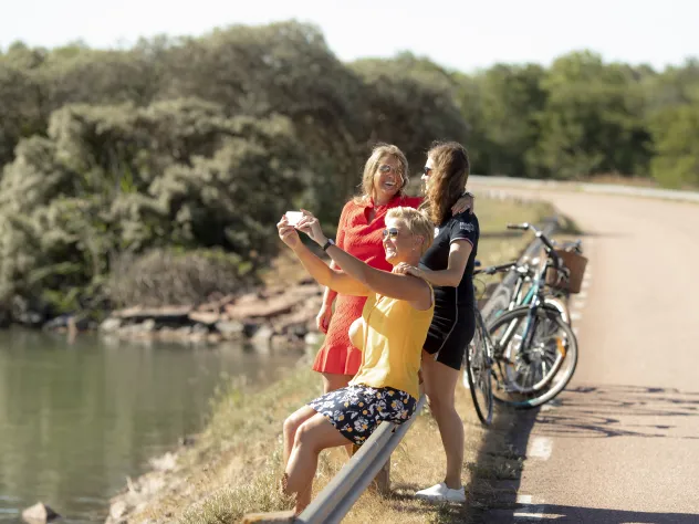 Kvinnor med cyklar som stannat vid brobank för fotografering.