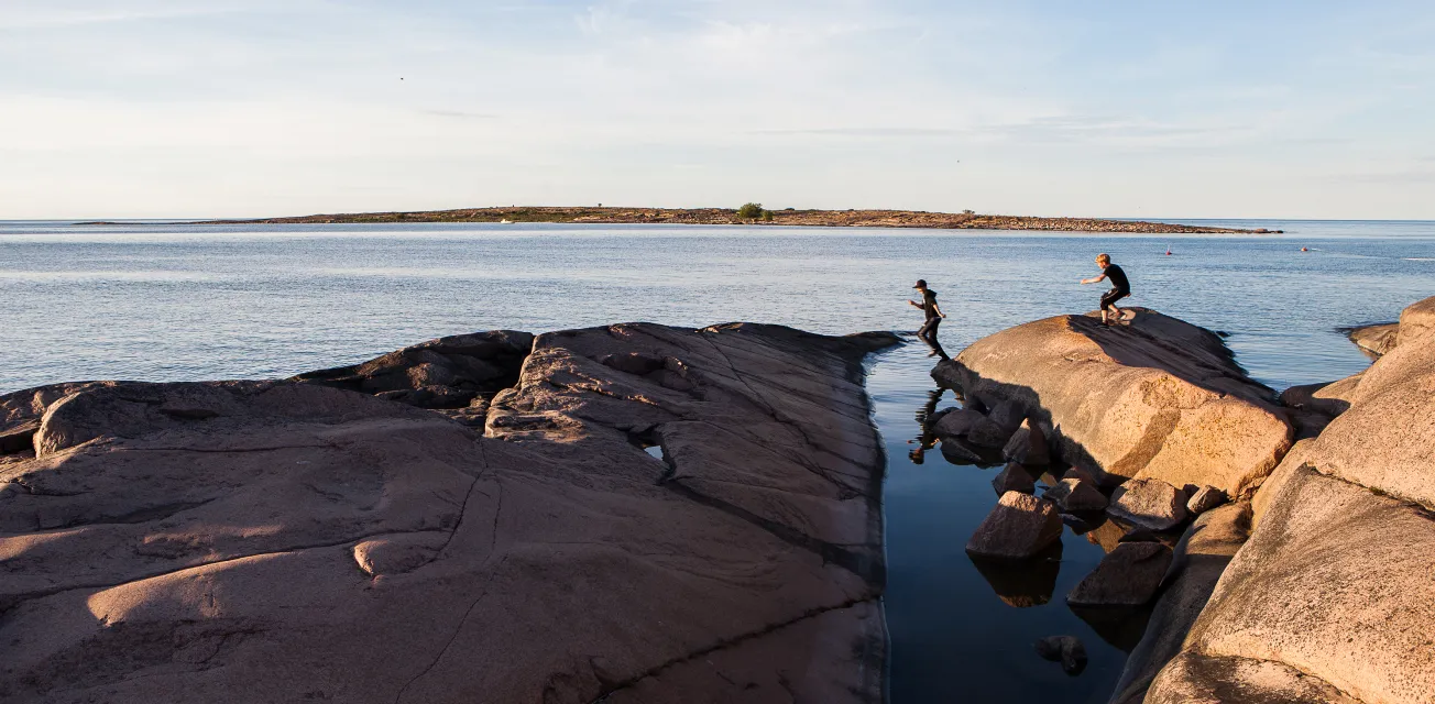 Pojkar som springer på granitröda klippor vid havet på ön Sälskär.