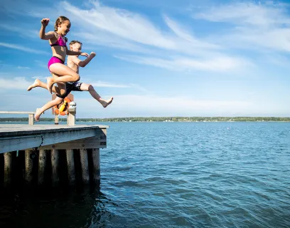 Barn som hoppar från bryggan vid badstranden Lilla Holmen i Mariehamn